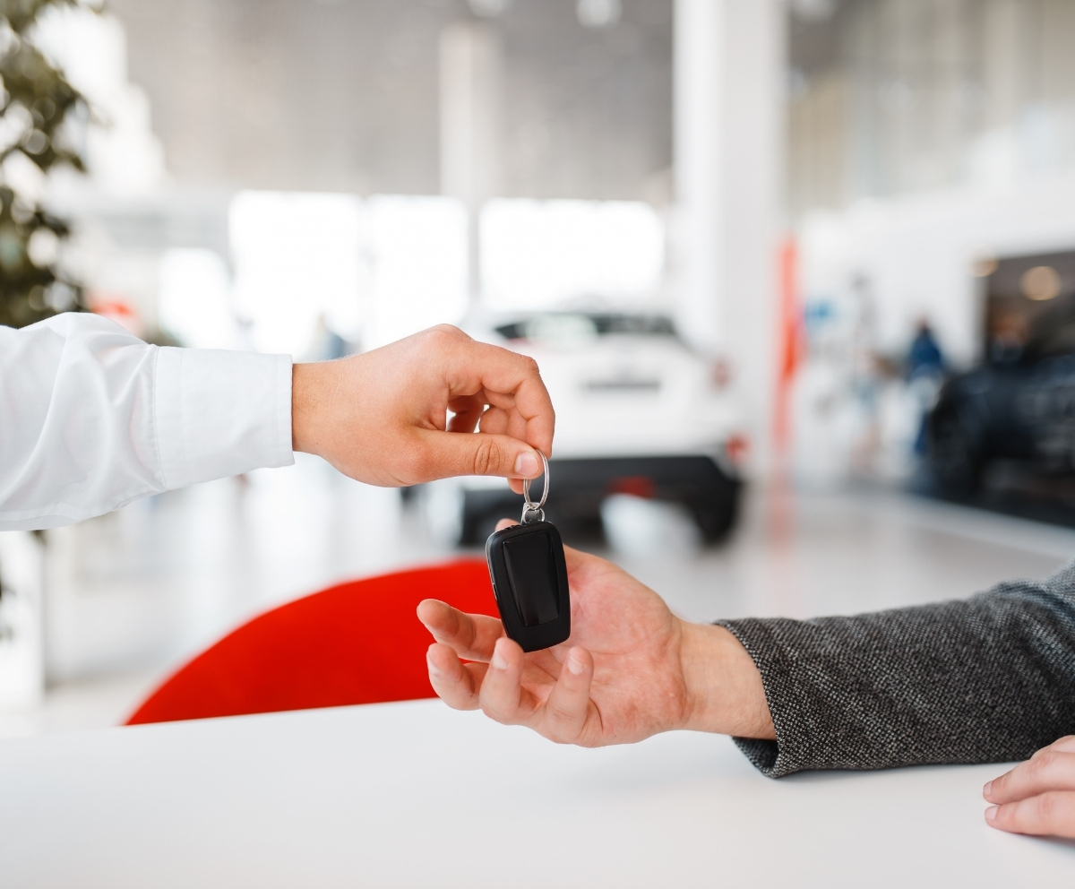car dealer handing over key for new auto
